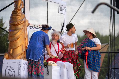 Aktor przebrany za Koziołka Matołka i inne postaci na scenie podczas dialogu.